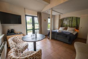 a living room with a bed and a table and chairs at Bed & Bos de 14 Sterren in Den Burg