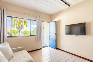 a living room with a couch and a flat screen tv at Guarajuba, apart 1/4 próximo à praia in Guarajuba