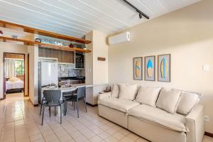 a living room with a couch and a kitchen at Guarajuba, apart 1/4 próximo à praia in Guarajuba