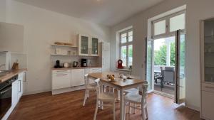 a kitchen with white cabinets and a table and chairs at Villa Sonneck, App 07 - Bade- & Saunawelt täglich inklusive in Ostseebad Sellin