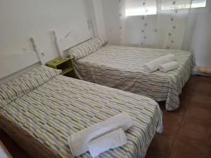 three beds with towels on them in a room at Ático Playa in Cartagena