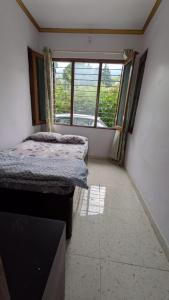 two beds in a room with a window at Kumaon Breeze homestay in Bhowāli