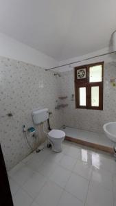 a bathroom with a toilet and a sink and a window at Kumaon Breeze homestay in Bhowāli