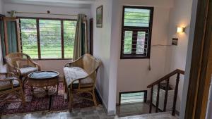 a room with chairs and a table and windows at Kumaon Breeze homestay in Bhowāli