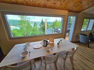 a dining room with a table and a large window at Les Reflets Verts - Lac de Vouglans in Maisod