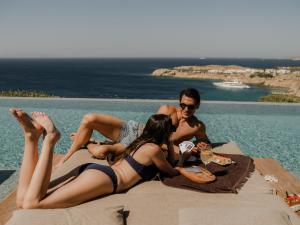 a group of people laying on a blanket next to a pool at Tropicana Suites & Villas Mykonos in Paradise Beach