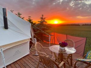 a tent with a table and chairs on a deck with a sunset at Thy Glamping in Hurup