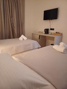 a room with two beds and a desk with a television at Apartmani KIKO in Međugorje