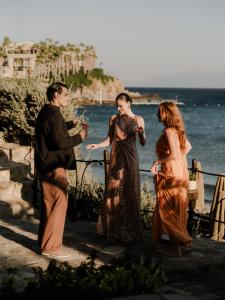 a group of three people standing next to the water at Tropicana Suites & Villas Mykonos in Paradise Beach