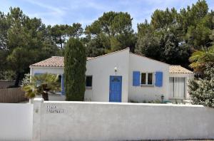 a white house with a blue door behind a fence at Villa du Bonheur Carambole in Saint-Georges-dʼOléron