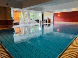 a swimming pool with blue tiles in a hotel room at ALPIN- Das Sporthotel, SUMMERCARD included May - September in Zell am See