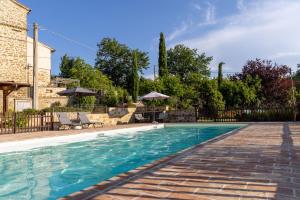 a swimming pool in a yard with chairs and umbrellas at Agriturismo La Palazzetta di Assisi in Assisi