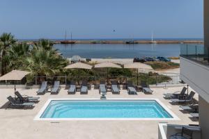 a swimming pool with chairs and umbrellas on a building at Amara Cove Adults Only by Estia in Malia