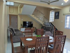 a living room with a table and chairs and a staircase at Malliga Farm House in Turinjāpuram