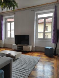 a living room with a flat screen tv and two windows at Le first République, gare centre ville in Bourgoin