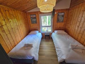 two beds in a room with wooden walls at Les Reflets Bleus in Maisod