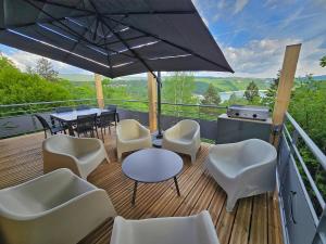 a deck with white chairs and tables and an umbrella at Les Reflets Bleus in Maisod