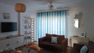a living room with a chair and a television at Ático Playa in Cartagena