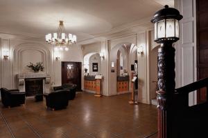 a lobby with chairs and a fireplace and a chandelier at Hotel Schloss Schweinsburg in Neukirchen-Pleiße