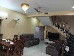 a living room with a couch a table and a tv at Malliga Farm House in Turinjāpuram