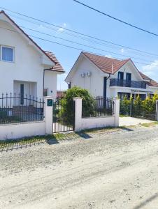 a white house with a fence on a dirt road at Chill Garden House in Satu Mare