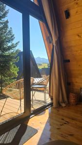 a balcony with chairs and a large glass window at Forest Whisper - Mountain Retreat in Kovačka Dolina