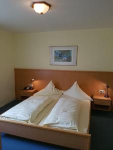 Hotel Stadt Baunatal في باوناتال: سرير كبير في غرفة نوم مع مواقف ليلتين
