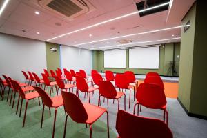 an empty room with red chairs and a projection screen at IBIS STYLES PETROLINA in Petrolina
