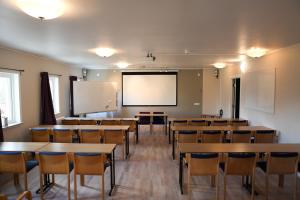 an empty classroom with tables and chairs and a whiteboard at Hotel Dalhem in Dalhem