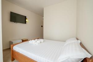 a bedroom with a white bed with a tv on the wall at Hotel Boutique Vioalv in Sarandë