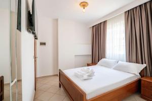 a bedroom with a bed with white sheets and a window at Hotel Boutique Vioalv in Sarandë