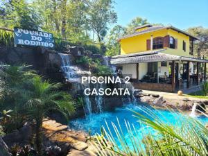 a waterfall in front of a restaurant with a water park at Pousada do Rodrigo in Macacos