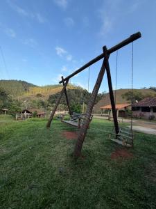 a swing set in a field with two benches at Recanto Pin in Alfredo Chaves
