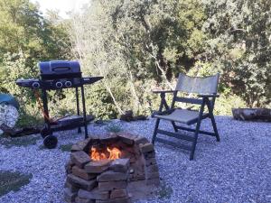 a grill and a chair next to a fire pit at Stone House Rooms near Kavala in Amisianá