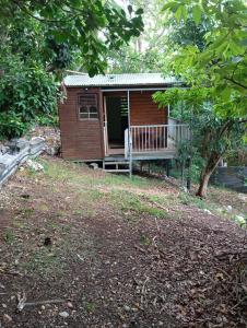 a small cabin with a porch and a deck at cabane dans le jardin in Morne-à-lʼEau