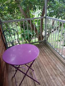 a purple table and chair on a wooden deck at cabane dans le jardin in Morne-à-lʼEau