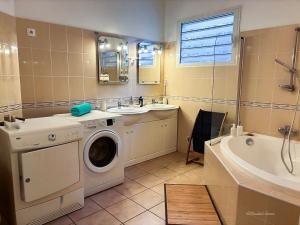 a bathroom with a washing machine and a sink and a tub at Ty Lodge Réunion, Piscine, Spa, Vue Océan, Jardin, entre Saint-Pierre et volcan in Le Tampon +29 photos
