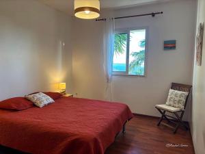 a bedroom with a bed and a window and a chair at Ty Lodge Réunion, Piscine, Spa, Vue Océan, Jardin, entre Saint-Pierre et volcan in Le Tampon
