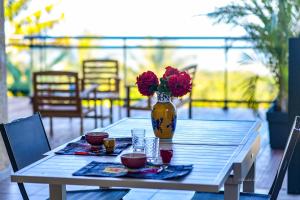 a wooden table with a vase with flowers in it at Ty Lodge Réunion, Piscine, Spa, Vue Océan, Jardin, entre Saint-Pierre et volcan in Le Tampon