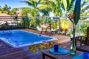 a pool on a deck with a chair and a table at Ty Lodge Réunion, Piscine, Spa, Vue Océan, Jardin, entre Saint-Pierre et volcan in Le Tampon