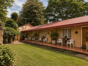 a house with chairs and tables in the yard at Anna Boeremeisie Guesthouse in Benoni