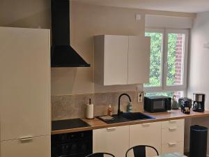 a kitchen with white cabinets and a sink at Le Forest Lodge 325 in Béthune +9 photos