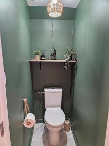 a bathroom with a toilet with plants on the wall at Le Forest Lodge 325 in Béthune