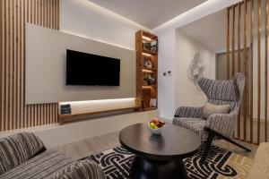a living room with a tv and two chairs and a table at The Encore Hotel Nakuru in Nakuru