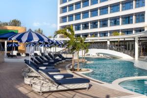 a pool with lounge chairs and umbrellas next to a building at The Encore Hotel Nakuru in Nakuru