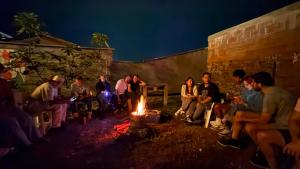 a group of people sitting around a fire at La Casa Rosada Hostel in Jericó