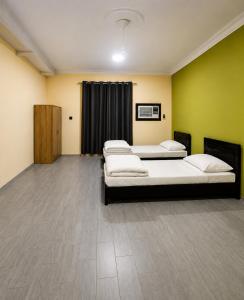 three beds in a room with green walls at Liva Residency in Salalah