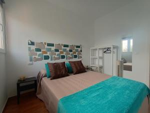 a bedroom with a bed with a blue comforter at La Casita de Héctor in Arinaga