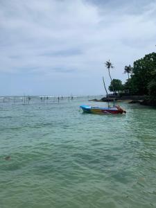 a boat sitting in the water on a beach at Lushy Glorious Hotel in Matara
