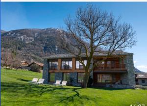 a house with two chairs and a tree in the yard at Chambre d'Hotes Vista Monte Bianco in La Salle
